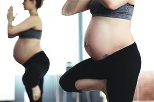 Pregnant woman performs yoga posture